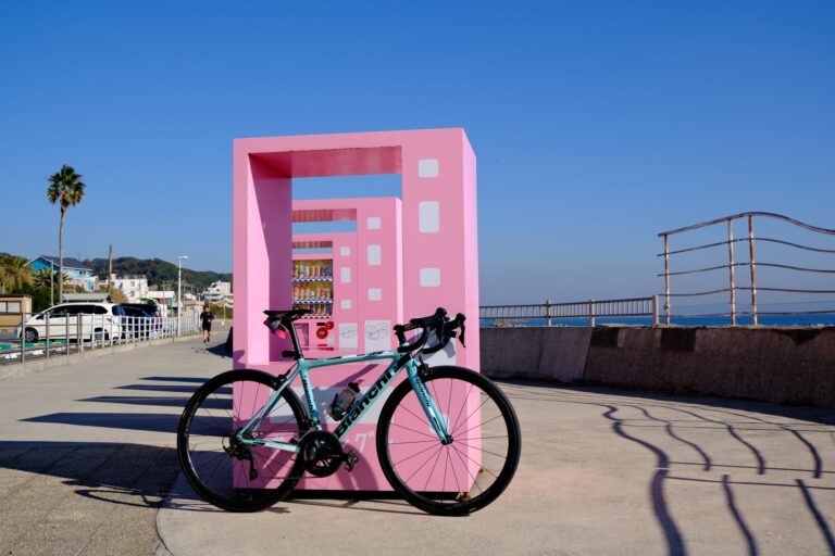 ピンクのオブジェの前に止めたチェレステカラーのロードバイク