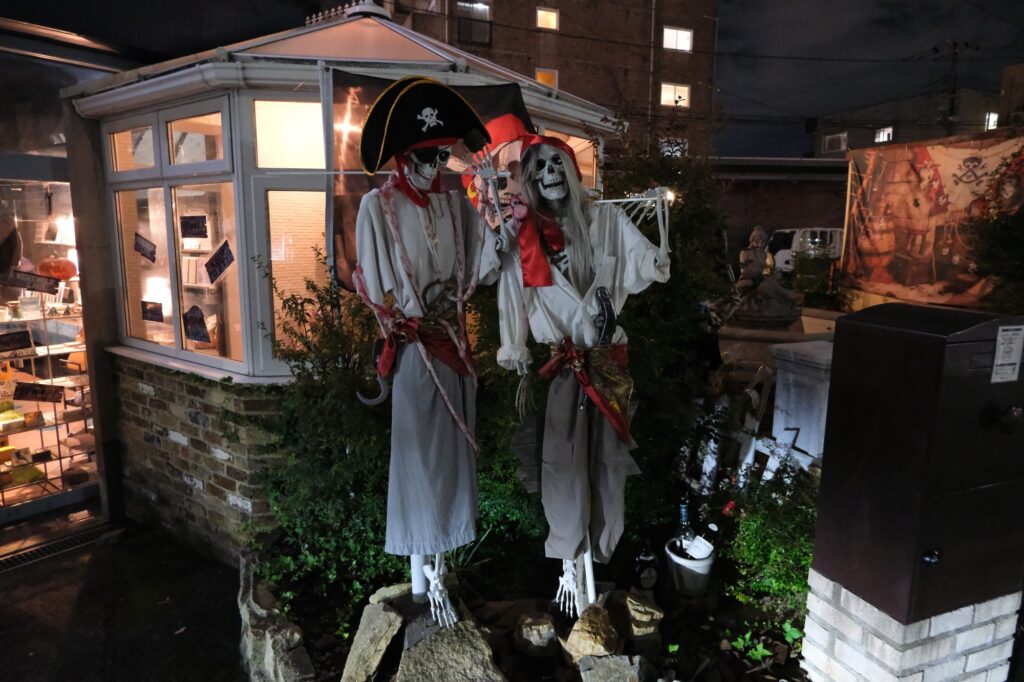 夜の店先に飾られた海賊姿のハロウィンの骸骨